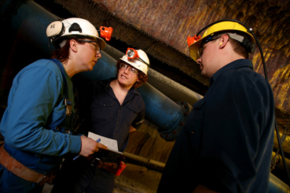 Une travailleuse et deux travailleurs discutent dans une mine souterraine