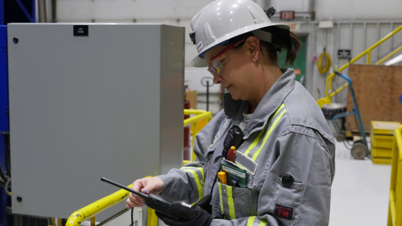 Aboriginal woman electrician examining a hand held radio