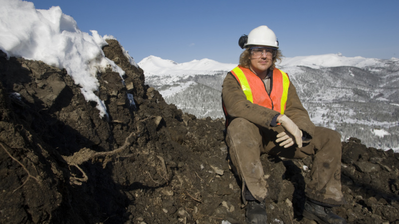 Jeune homme assis sur un rocher dans un paysage montagneux